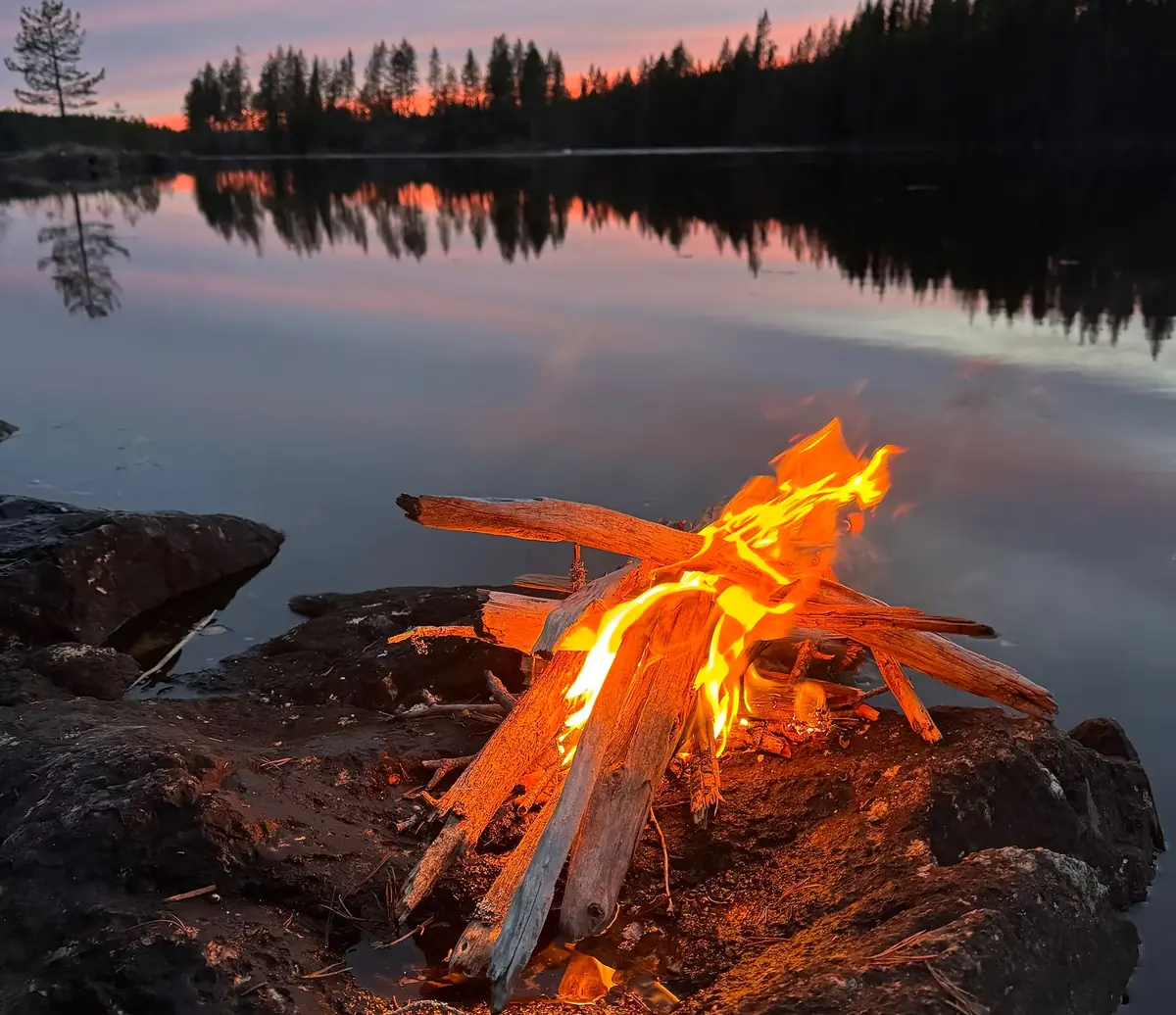 Lägereld vid en sjö i skymning